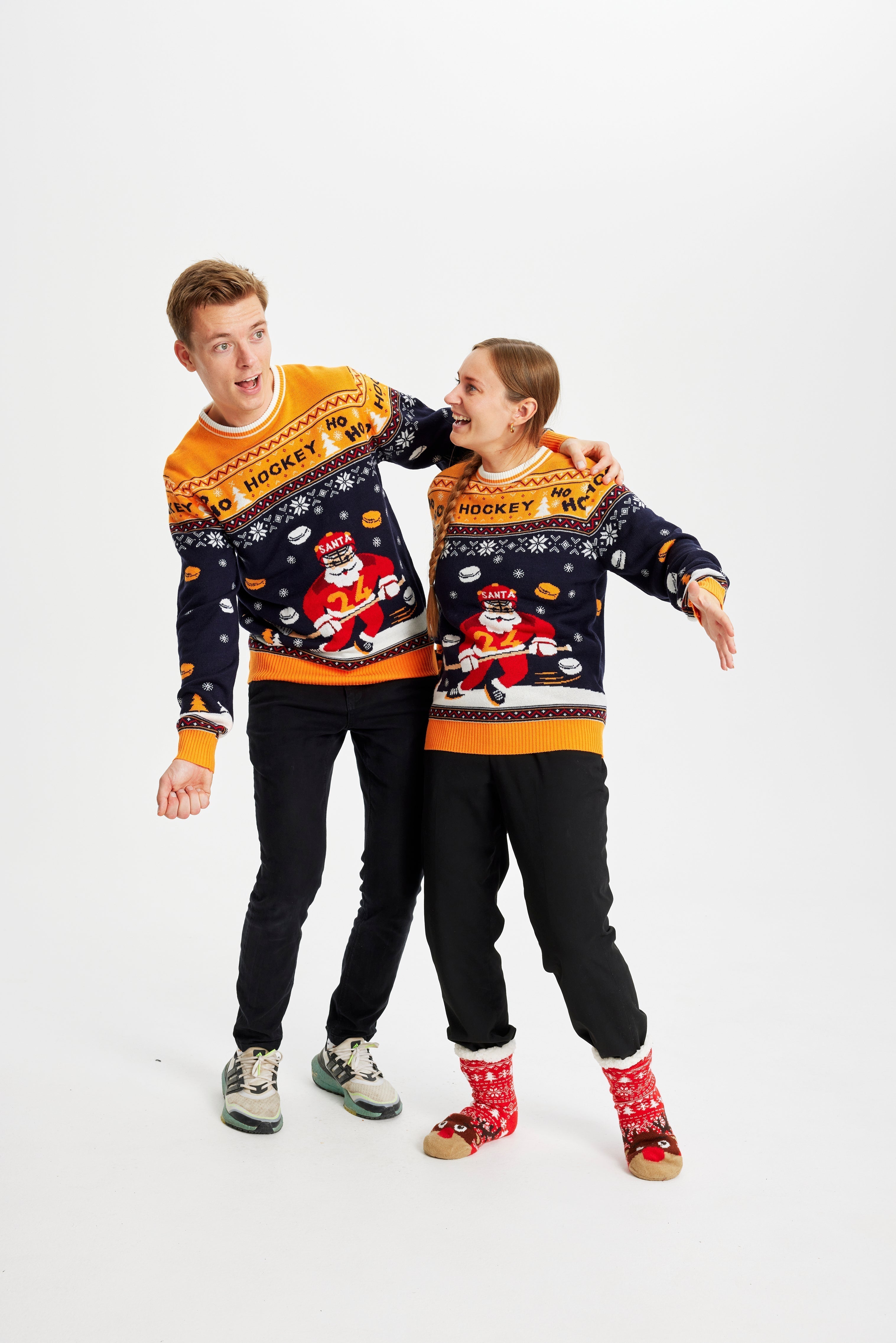 Una coppia che indossa un maglione natalizio giallo e blu con sopra un Babbo Natale che gioca a hockey.